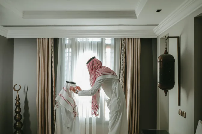 Lifestyle photography of a Saudi guest by the window of a hotel room