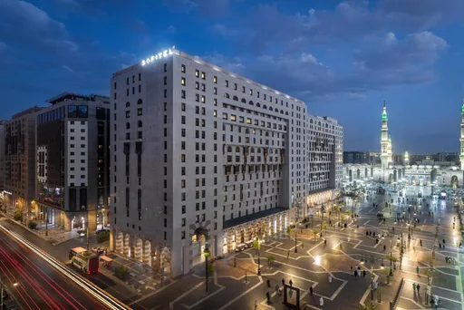Sofitel hotel exterior at dusk beside the Prophet's Mosque plaza in Madinah