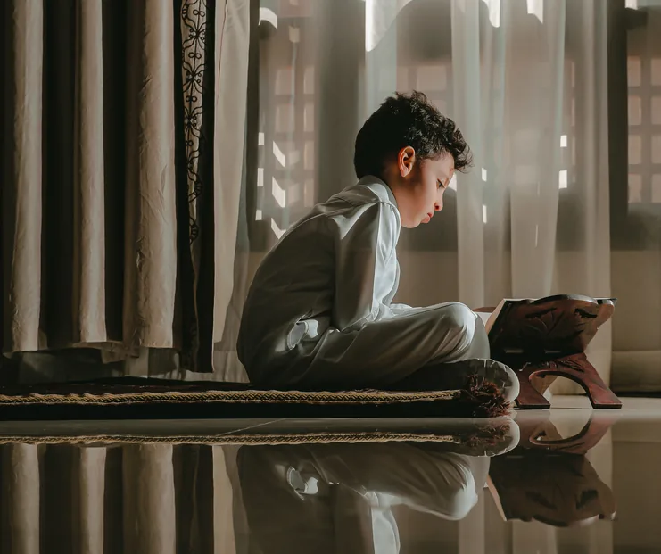 Boy reading the Quran in soft window light